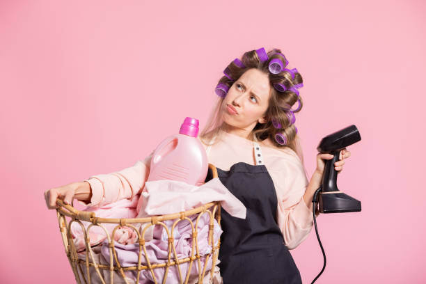 istock The woman is thinking about household chores, she has applied rollers screwed on head holds a wicker basket with clothes and washing liquid in the other hand ironing steamer 1423593714