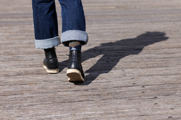 Woman's feet and legs as she walks away from the viewer on a wooden deck.