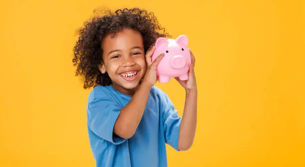 Photo of Happy ethnic boy storing money in piggy bank