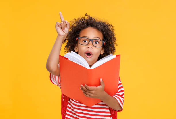 istock Smart ethnic schoolboy in glasses reading book 1423602286