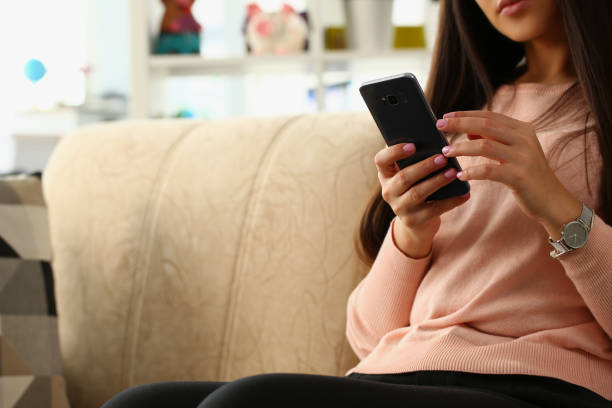 istock Woman using smartphone sitting on sofa at home 1423602432