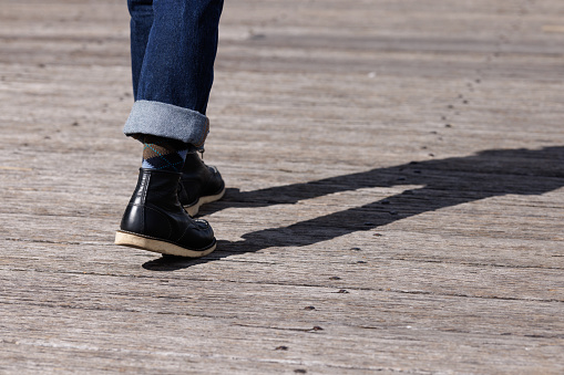 Woman's feet and legs as she walks away from the viewer on a wooden deck.