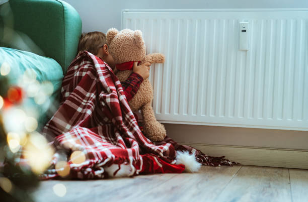 istock cute little boy wrapped id plaid sitting by heater warming teddy bear paws 1423602766