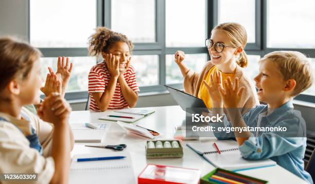 Teacher And Joyful Students Celebrate Successful Completion Of Collective School Work In A Bright Classroom Stock Photo - Download Image Now