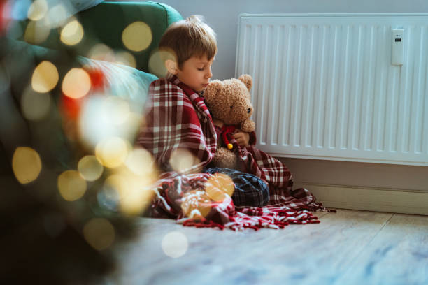 istock cute little boy wrapped id plaid sitting by heater 1423603320