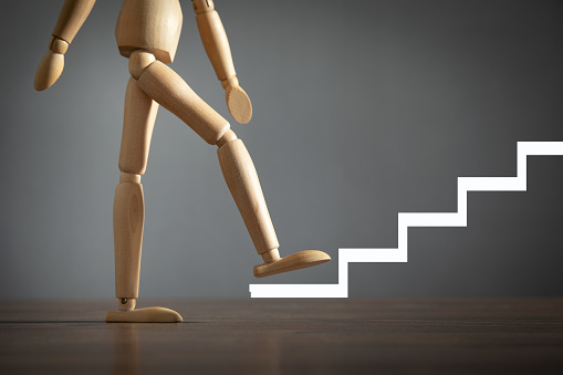 Wooden human figure climbing in stairs. Business. Career