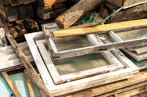 A dump of old wooden window frames with glass. Recycling of materials, environmental problems and collection of waste and construction waste. High quality photo
