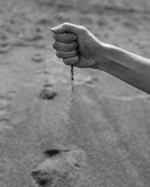 Man pouring sand through hand in desert