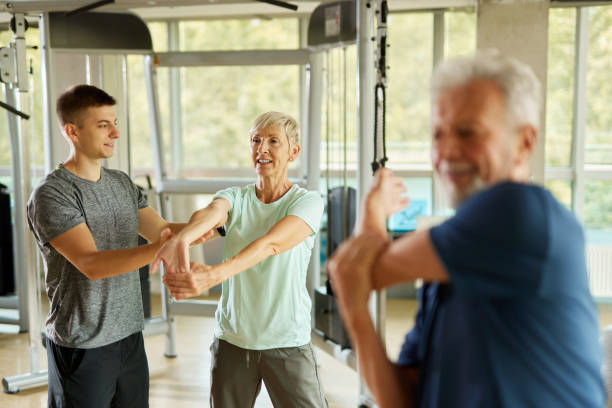 istock Senior couple doing stretching exercises with personal trainer at the gym 1423608125