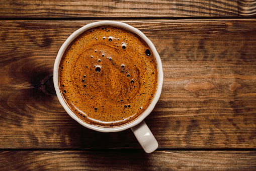 Cup of coffee closeup on dark wooden background, top view , flat lay