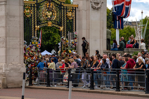 London, England, United Kingdom - September 17, 2022: The Mall lined with Union Jack flags in front of Buckingham Palace with 2 policemen and a small crowd crossing - preparations for the funeral of Queen Elizabeth II