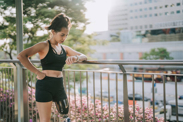 istock Asian female athlete with disability artificial leg checking her heart beat electrocardiography with fitness tracker at pedestrian walkway bridge after jogging in the morning 1423617253