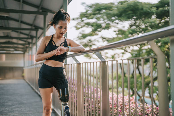 istock Asian female athlete with disability artificial leg checking her heart beat electrocardiography with fitness tracker at pedestrian walkway bridge after jogging in the morning 1423617268