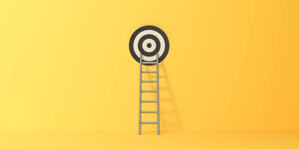istock Step ladder and target on a yellow wall with copy space 1423619896