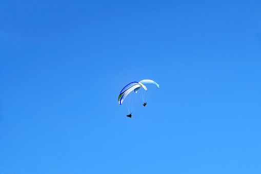 Two paraglider on blue sky.