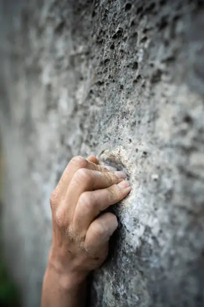 Close up shot of an adult male handholding on to a rock, illustration for rock climbing.