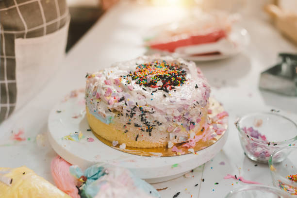 Messy kitchen with homemade birthday cake made from kids. Kitchen with ingredients for baking on working table. Messy table full with pastries items and ingredients.