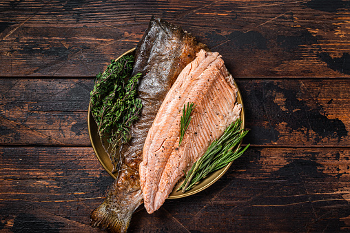 Baked Trout fillet, roasted fish on a plate with thyme and rosemary. Wooden background. Top view.