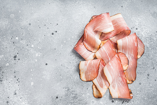 Black Forest Ham Slices on kitchen table. Gray background. Top view. Copy space.