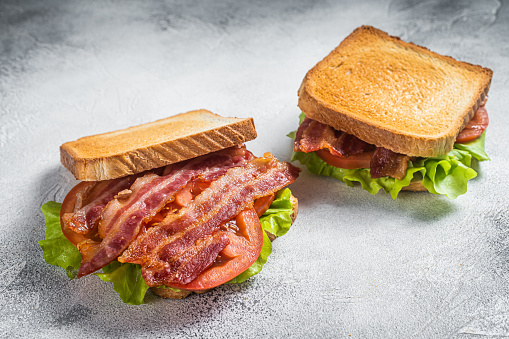 BLT toasted sandwich with bacon, tomato and lettuce. Gray background. Top view.