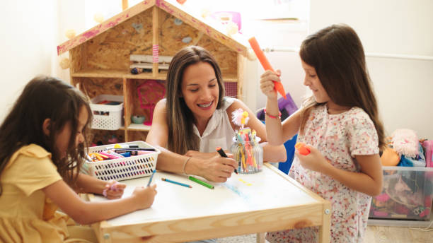 istock Smiling mother and two daughters drawing together at home 1423623279