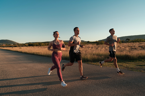 Three runners sprinting outdoors - Sportive people training in a urban area, healthy lifestyle and sport concepts. High quality photo