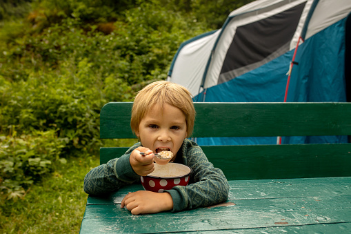 People, children enjoying the amazing views in Norway to fjords, mountains and other beautiful nature miracles, having breakfast while wild camping