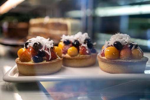 Side view of a fridge display with fruits tarts in a bakery shop