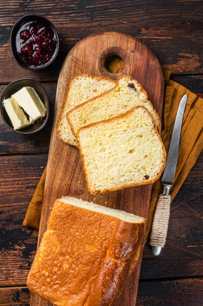 istock Brioche bread on breakfast table with butter and jam. Wooden background. Top view 1423628446