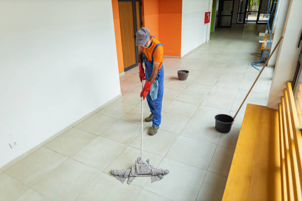 Senior adult janitor mopping floor at school