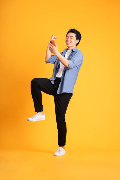 istock full body image of asian man posing on yellow background 1423630780