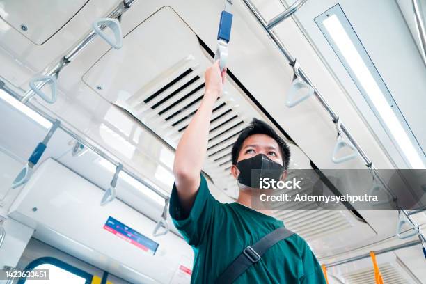 Asian Passenger Man Wearing Protective Face Mask And Standing Inside Mrt Jakarta Train At Railway Platform While Traveling To Work Jakarta Indonesia Stock Photo - Download Image Now