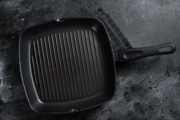 istock Empty cast-iron grill pan for cooking  on rustic towel. Black background. Top view. Copy space 1423633539