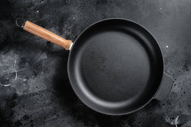 istock Empty cast-iron skillet for cooking  on rustic towel. Black background. Top view. Copy space 1423633571