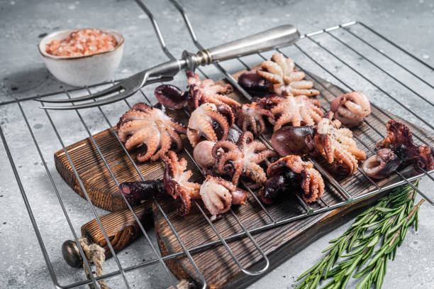 istock Grilled baby mini octopuses on a grill. Gray background. Top view 1423634143