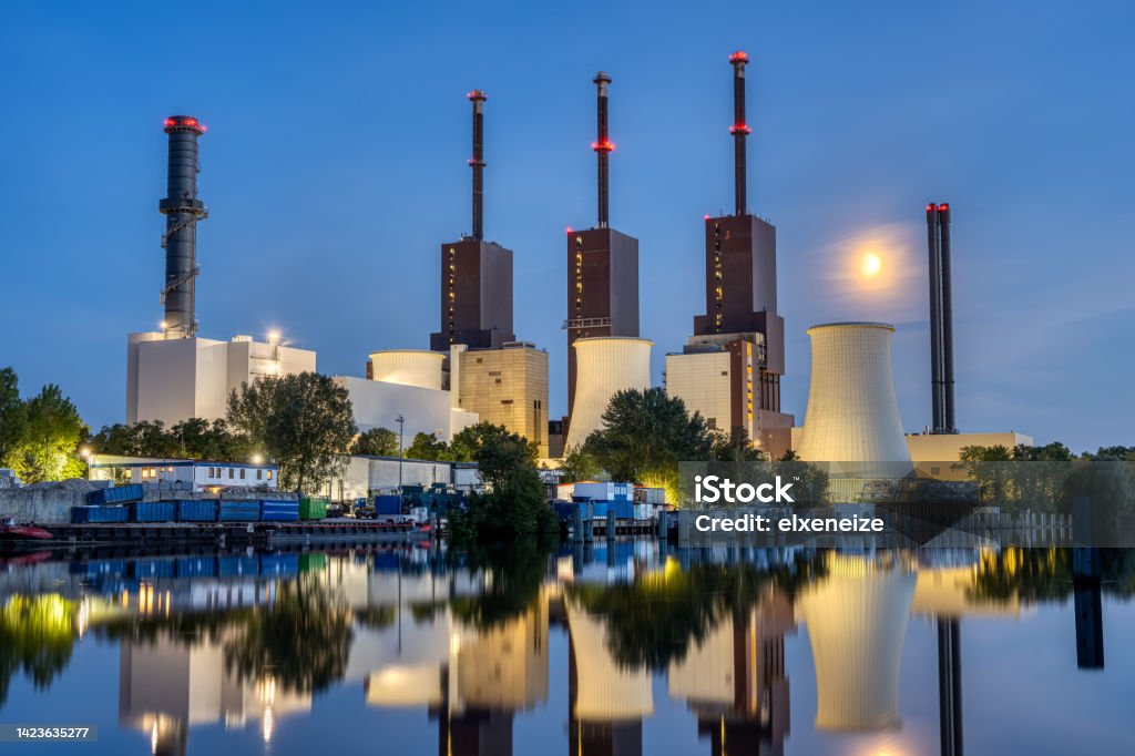 A thermal power station in Berlin at nightberlin, building, canal, chimney, chimneys, climate change, co2, cogeneration, Combined heat and power, dusk, electricity, energy, Energy Crisis, energy supply, environmental, gas crisis, generate, generation, ger A thermal power station in Berlin at night reflected in a canal Cogeneration Stock Photo