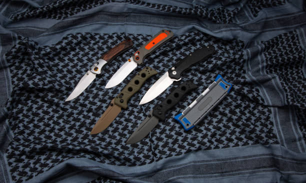 istock Compact metal sharp knife with a folding blade. Pocket folding knives on a fabric background. 1423636362