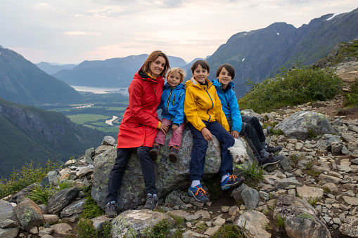 Family with children and dog, hiking in Litlefjellet on sunset, enjoying amazing view from the top of hiking trail Romsdalen