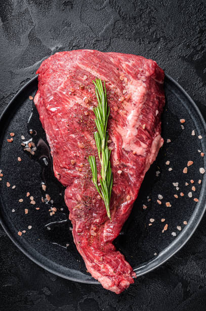 temperado cru tri-tip carne bife no prato. fundo preto. vista superior - meat roast beef tenderloin beef - fotografias e filmes do acervo
