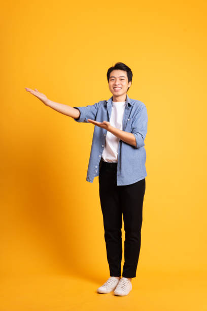 istock full body image of asian man posing on yellow background 1423637387