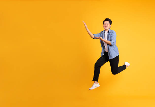 istock full body image of asian man posing on yellow background 1423637521