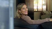 istock Happy, relax and woman on sofa in living room with smile in comfortable home looking back in joy. Portrait of a beautiful female relaxing on couch in comfort smiling in happiness, joy and lounge 1423638219