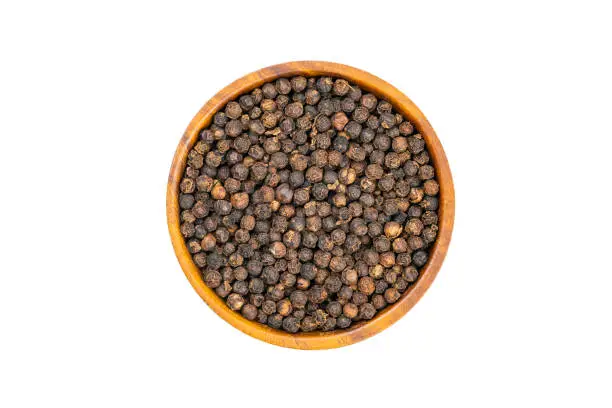 Top view or flat lay of fresh raw black pepper in wooden bowl isolated on white background with clipping path.