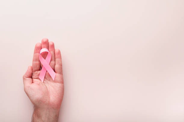 Pink Breast Cancer Awareness Ribbon. Hands holding pink ribbon on backgrounds. Breast cancer awareness and October Pink day, world cancer day. Top view. Mock up. stock photo