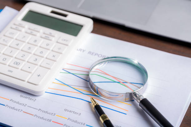 istock magnifying glass with business document financial paper chart statistic report on desk in office, closeup calculating machine with paperwork on table concept for analysis, market, banking 1423644256