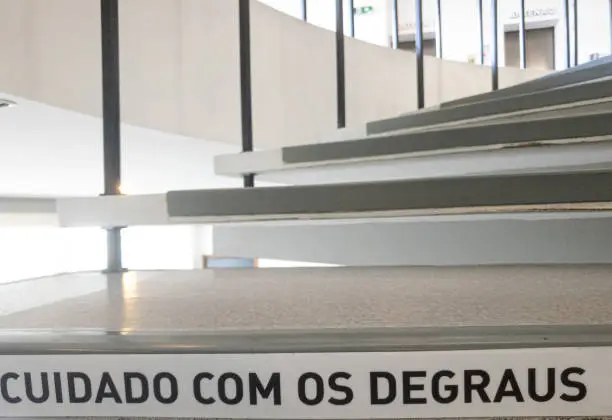 spiral stairs with the warning phrase written in Portuguese, "cuidado com os degraus".