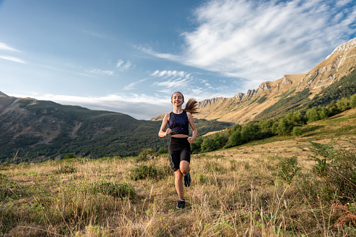 Girl in Sportswear Trail Running Outside in Nature, on the Alpine Meadow