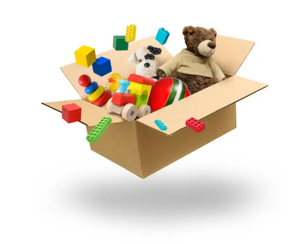 Photo of Cardboard box full of various toys levitation over white background