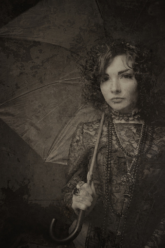 Elegant old fashioned vintage lady with umbrella posing over dark background