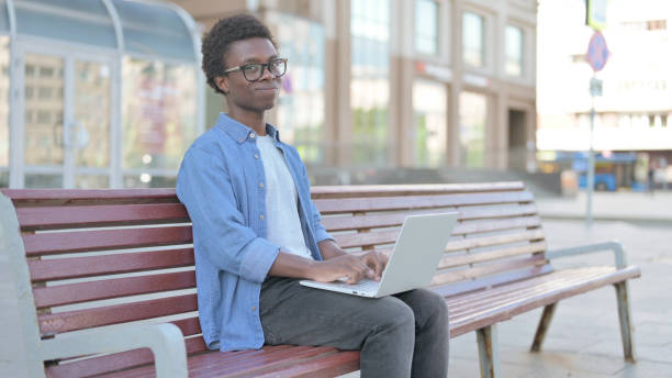 istock Rejecting Young African Man in Denial While using Laptop Sitting Outdoor on Bench 1423655857